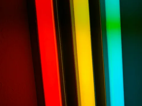 Three bars of light. From left to right: Red, yellow, and cyan. The bars of light are three dimensional showing some depth in a rectangular shape.