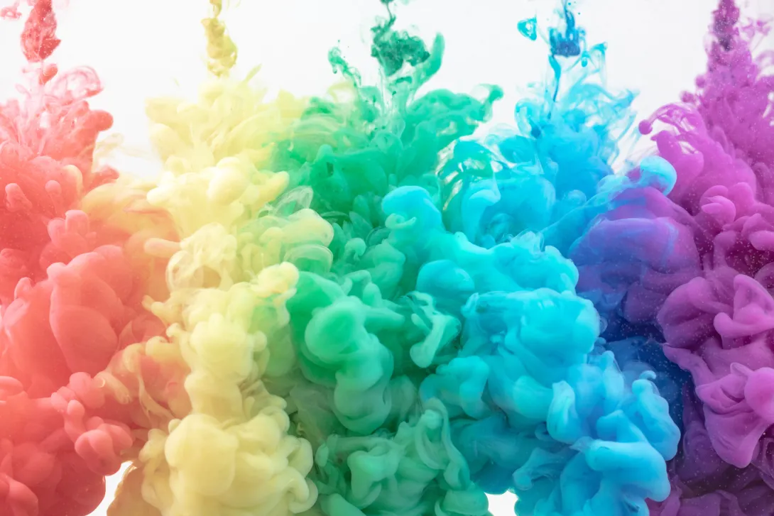 An explosion of colors with 5 plumes of colored smoke rising up to form a rainbow colored red, yello, green, cyan, and magenta